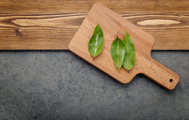 The bay leaves on cutting board set up on shabby wooden background with copy space . - Photo, Image