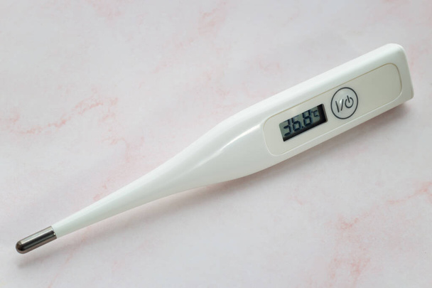Een moderne elektronische medische thermometer voor het meten van de lichaamstemperatuur en het detecteren van coronavirusinfectie. - Foto, afbeelding