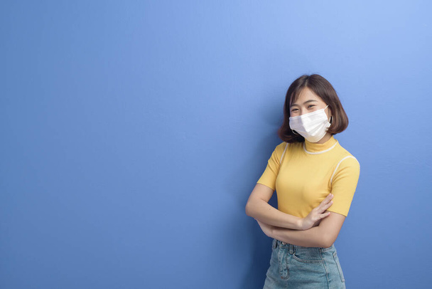 A portrait of young beautiful asian woman wearing a surgical mask over studio background, covid19 pandemic and air pollution (pm2.5). - Foto, afbeelding