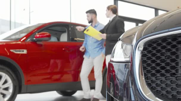 Értékesítői és férfi ügyfél vizsgálja autó autókereskedés - Felvétel, videó