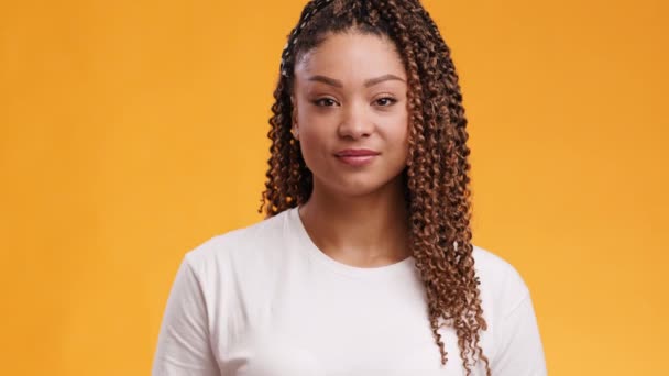 Fiatal hűvös afro-amerikai nő bemutató OK gesztus és mosolygós kamera, narancs stúdió háttér - Felvétel, videó
