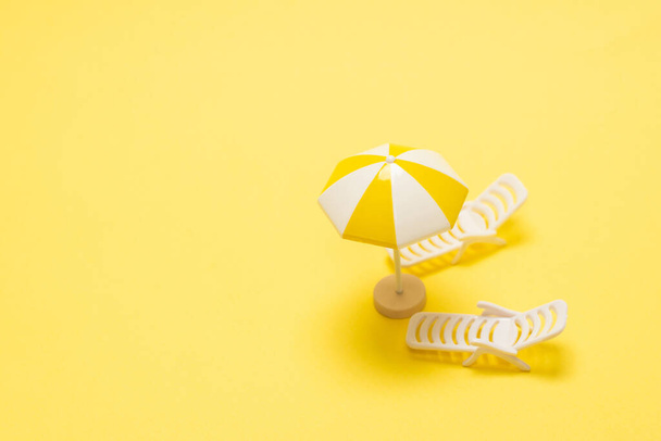 Sun lounger and yellow umbrella on a yellow background. - Photo, Image