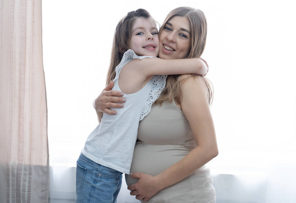 Caucasian happy little girl with blonde pregnant mother. hugs Together. - Fotografie, Obrázek