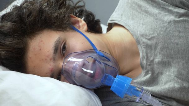  oxygen mask on the face of a guy lying on a bed in a hospital - Фото, зображення