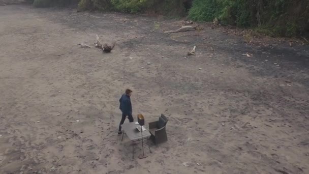 Top-view drone záběry muže na služební cestě v tropické destinaci, pracuje na notebooku sedí na pláži sám - Záběry, video