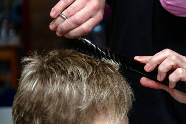 Fryzjer obcina młodej kobiecie włosy podczas kwarantanny w jej domu. Kowid-19. - Zdjęcie, obraz