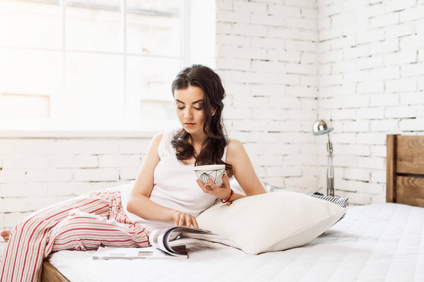 Женщина в постели пьет чай. Женщина наслаждается чаем в постели по утрам. - Фото, изображение