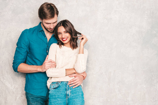 Portrait of smiling beautiful woman with red lips and her handsome boyfriend. Happy cheerful family posing in studio near gray wall.Valentine's Day. Models hugging. Concept of love - Photo, Image