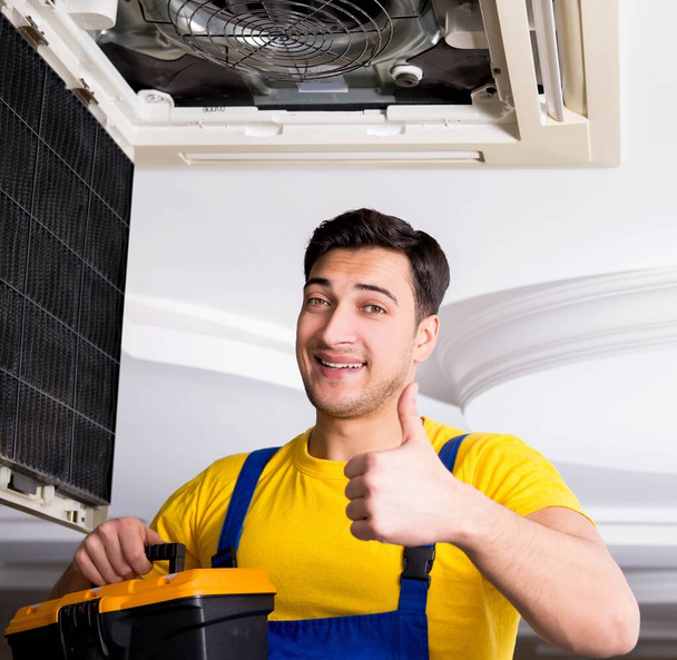 Repairman repairing ceiling air conditioning unit - Foto, afbeelding