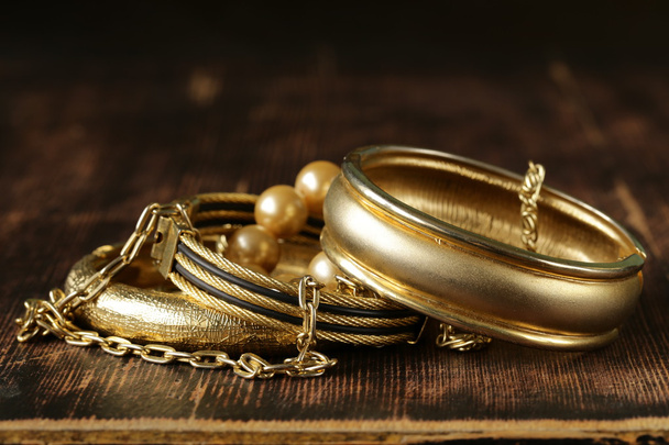 ヴィンテージの木製の背景に金と真珠のジュエリー - 写真・画像