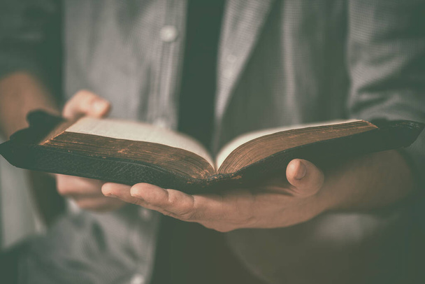 Dirty hands holding an old bible. Very short depth-of-field - Фото, изображение