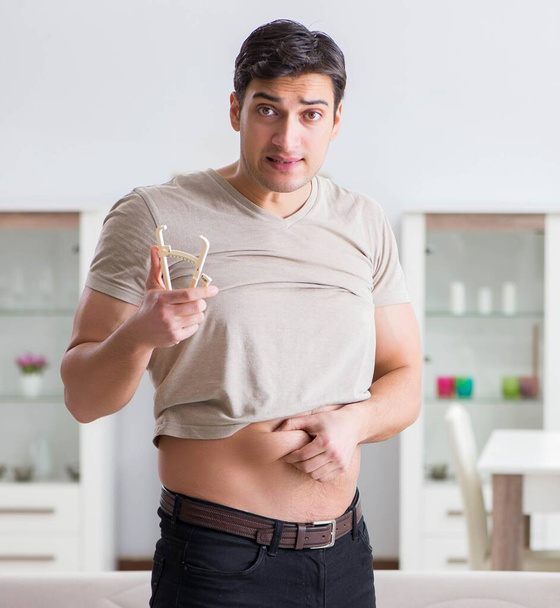 Hombre midiendo grasa corporal con pinzas - Foto, imagen