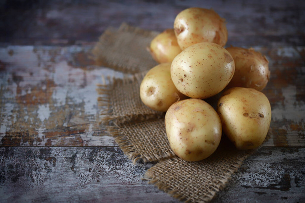Surowe ziemniaki na drewnianej powierzchni. Koncepcja zbioru ziemniaków. - Zdjęcie, obraz