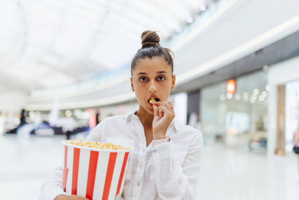 young cute woman holding popcorn in the mall background - Foto, immagini