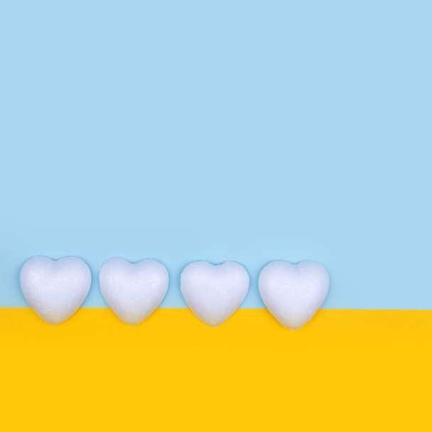 Corazones blancos sobre fondo amarillo y azul. Composición mínima del espacio de copia del día de San Valentín. - Foto, imagen