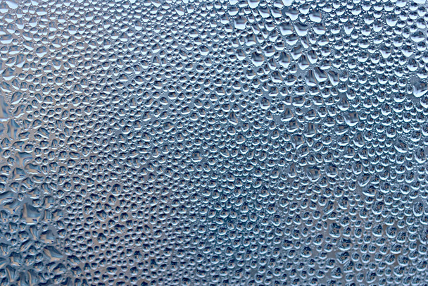 Malé kapky kondenzace, které se objevily na skle v zimě, vytvořily strukturovaný vzor. Kvalitní fotografie - Fotografie, Obrázek