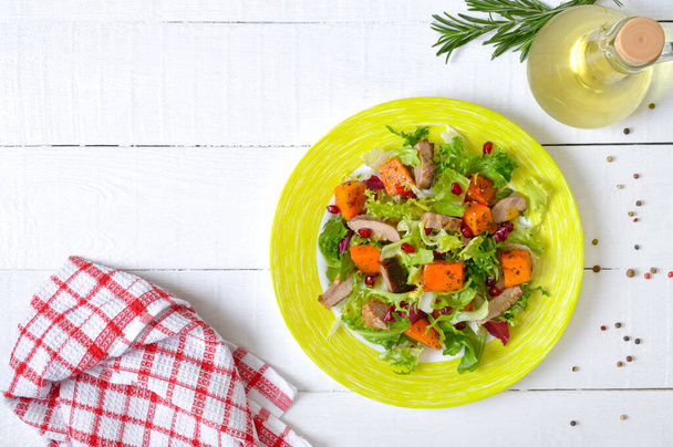 Dietary salad with roast turkey, pumpkin and green lettuce on a white wooden background. Top view. - Photo, Image