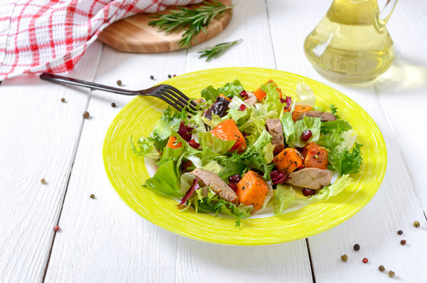 Dietary salad with roast turkey, pumpkin and green lettuce on a white wooden background. - Photo, Image