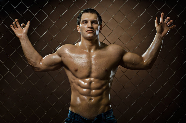 Muscular  guy on  netting   steel fence - Foto, Imagem