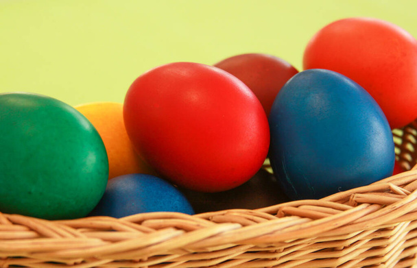 Цветные окрашенные пасхальные яйца в деревянную корзину украшения в рамках подготовки к празднику. Живопись курицы или утиных яиц является христианской традицией праздновать Пасху во всем мире. - Фото, изображение
