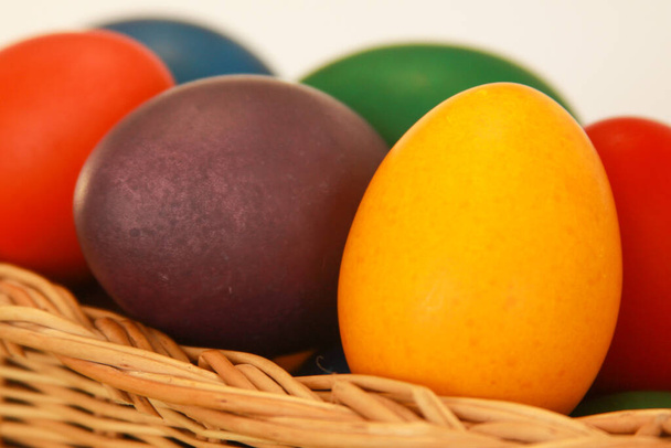 Kolorowe malowane pisanki w drewnianej dekoracji koszyka w ramach przygotowań do wakacji. Malowanie jaj z kurczaka lub kaczki to chrześcijańska tradycja obchodzenia Wielkanocy na całym świecie. - Zdjęcie, obraz