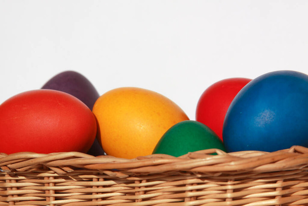 Kolorowe malowane pisanki w drewnianej dekoracji koszyka w ramach przygotowań do wakacji. Malowanie jaj z kurczaka lub kaczki to chrześcijańska tradycja obchodzenia Wielkanocy na całym świecie. - Zdjęcie, obraz