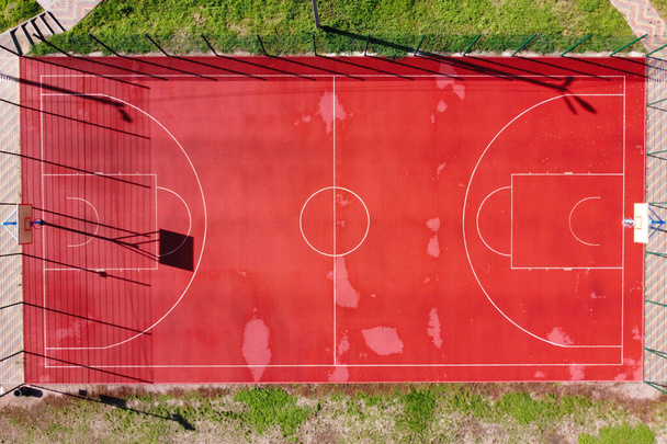 Pohled na basketbalové hřiště z dronu. Letecký pohled na prázdné hřiště basketbalu se zelenou trávou kolem. Přímo nad zobrazením. - Fotografie, Obrázek