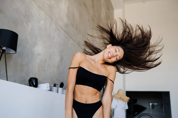Young attractive girl in black lingerie shaking her head with hair - Fotoğraf, Görsel