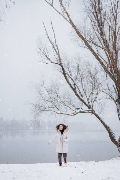 雪の川の岸を走っている少女 - 写真・画像