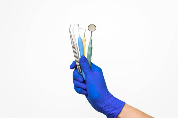 Dentyści trzymają w ręku niebieską rękawicę instrumenty dentystyczne. Reklama usług stomatologicznych i stomatologicznych - Zdjęcie, obraz