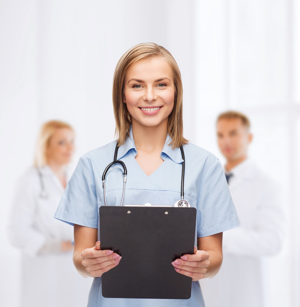 Smiling female doctor or nurse with clipboard - Valokuva, kuva