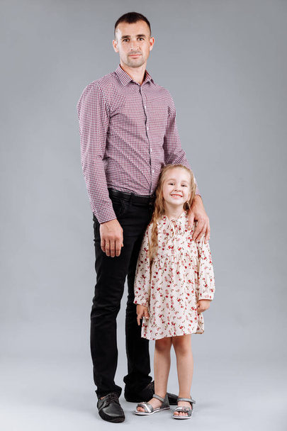 Felice padre e la sua figlioletta su sfondo grigio. - Foto, immagini