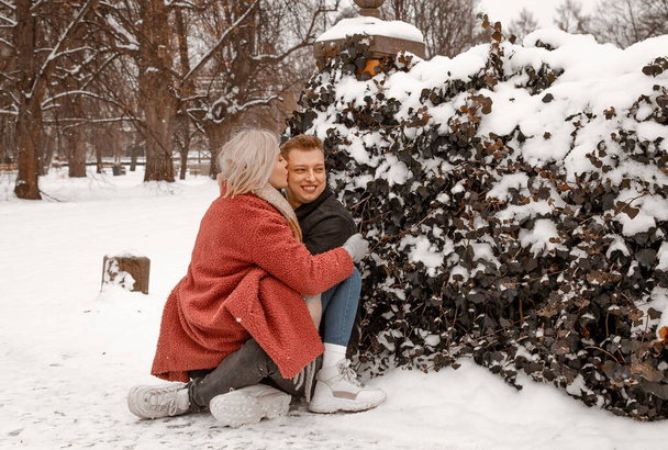 Outdoor waist up portrait of young beautiful happy smiling couple posing on street. Copy, empty space. Embracing dates in winterwear looking at camera in natural environment. Snow. Winter Vacation. - Foto, Imagem