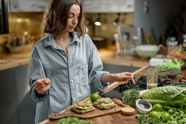 Piękna kobieta ze zdrowym zielonym jedzeniem w kuchni - Zdjęcie, obraz