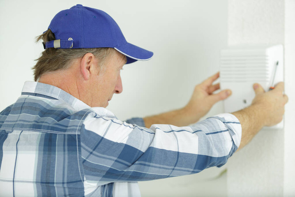 tradesman fixing electrical issue with hand dryer - Foto, Imagen
