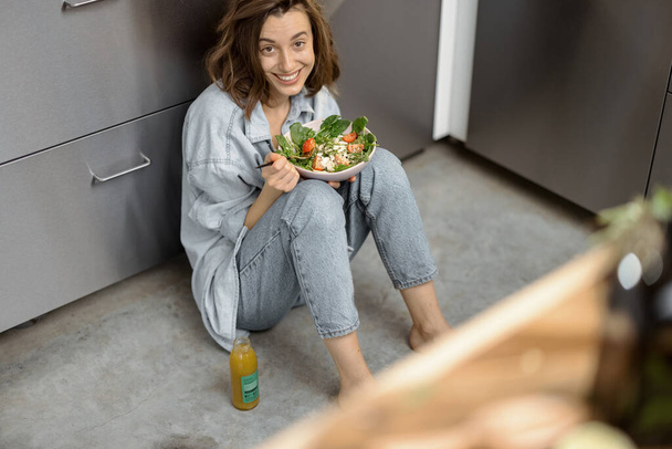 Женщина со здоровым салатом на кухне - Фото, изображение