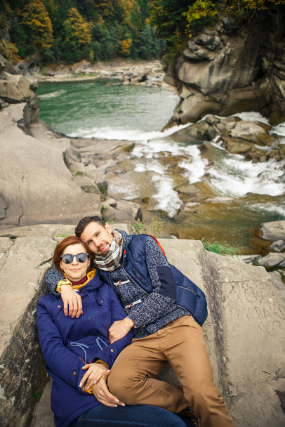 young beautiful couple travelers take a photo on the background of the river and forest - Fotografie, Obrázek
