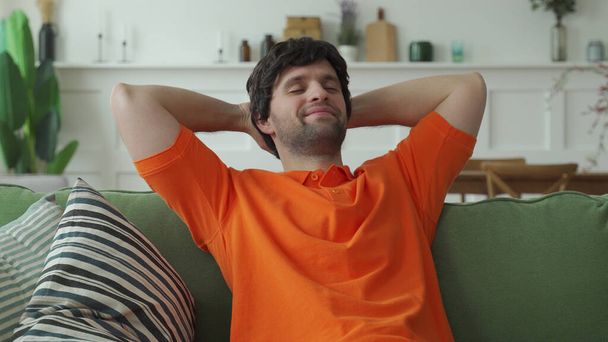 Happy man is resting on a comfortable sofa, resting with his eyes closed - Photo, Image