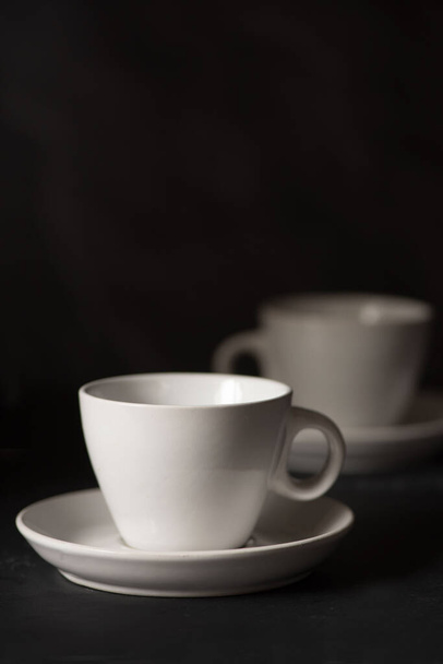 Kaksi tyhjää espressokuppia sivulta katsottuna mustaa taustaa vasten  - Valokuva, kuva