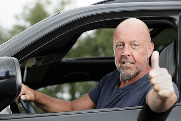 mature man driving car shows thumb up - Foto, imagen