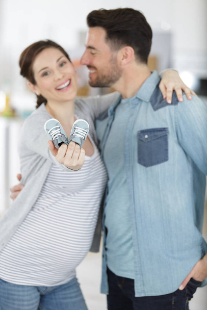 pregnant couple holding newborn shoes in hands - Fotó, kép