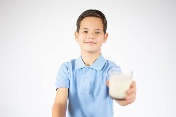 ute boy in blue shirt holding glass of milk on white background - Фото, изображение