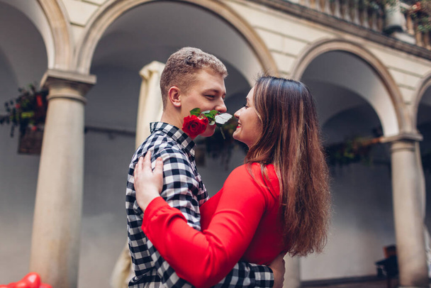 Día de San Valentín cita romántica. Novio y novia bailando tango con rosa en los dientes. Pareja divirtiéndose en el patio italiano en la ciudad de Lviv - Foto, imagen