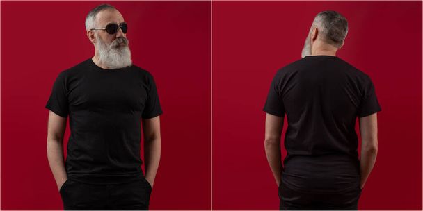 Volwassen knap seniorenmodel met een grijze baard in een wit t-shirt. Achteraanzicht. Mock up ruimte voor uw logo of ontwerp over donkerrode backgroun - Foto, afbeelding
