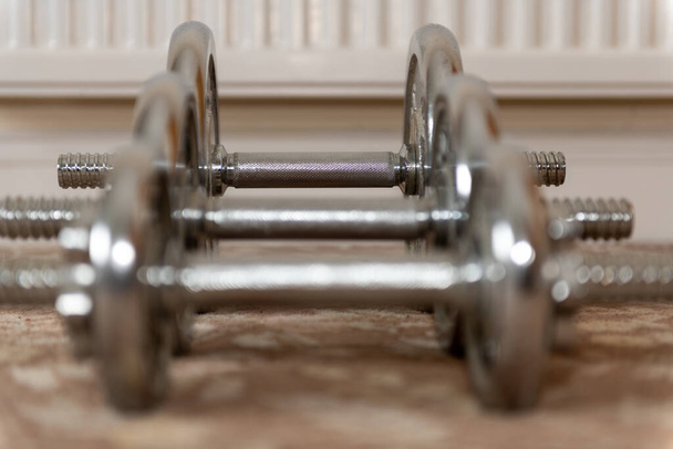 Close-up van een rij halters op de vloer gericht op de zwaarste halter op de achtergrond - Foto, afbeelding