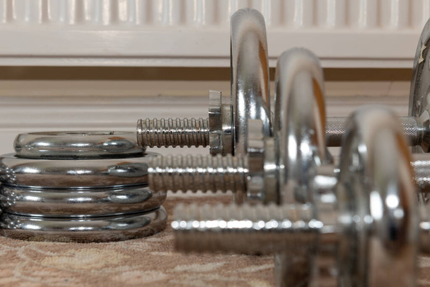 Close up of a row of dumbbells on the floor focusing on the biggest weight in the background - Photo, Image