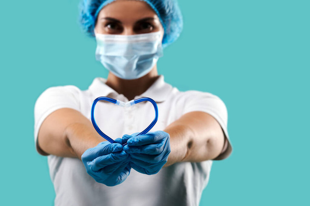 Close up de saliva ejetor na forma de coração nas mãos dentista feminino isolado em um fundo azul - Foto, Imagem