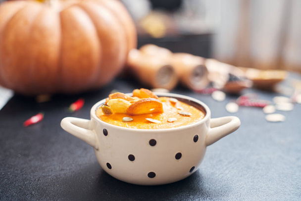 pumpkin cream soup with croutons on a black table with spices - Photo, image