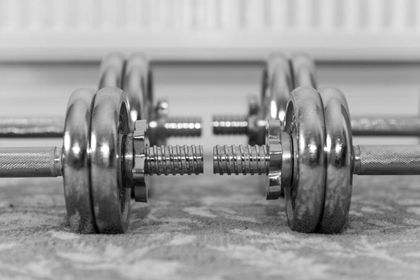 Black and white photo of dumbbells on the floor at home - Photo, Image