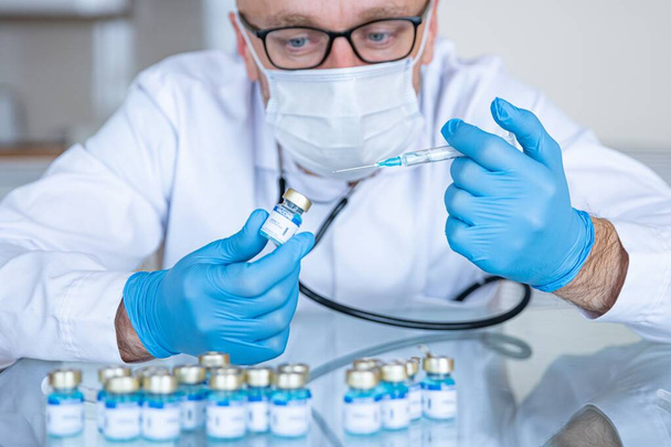 Γιατρός στο εργαστήριο με ιατρική μάσκα και γάντια ετοιμάζει εμβόλια για τον κορωναϊό.. - Φωτογραφία, εικόνα